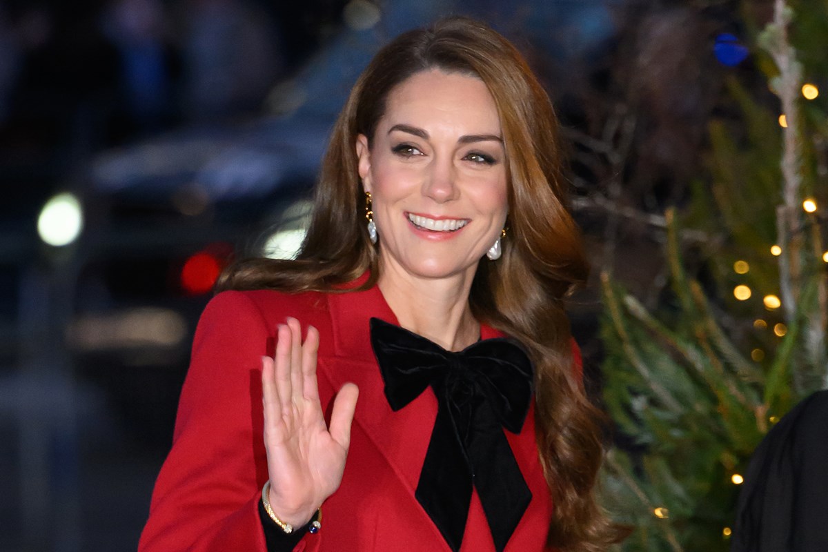 Foto colorida de mulher com cabelo longo, roupa vermelha com laço preto - Metrópoles