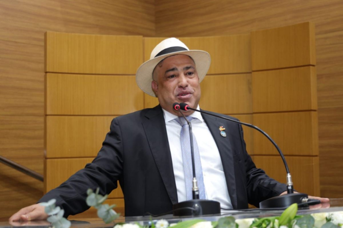 Foto colorida de homem de terno e chapéu estilo Panamá em plenário
